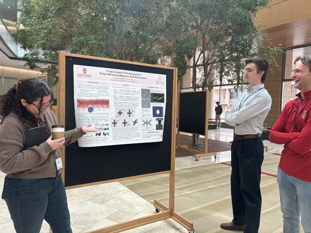 Three graduate students standing next to a poster board